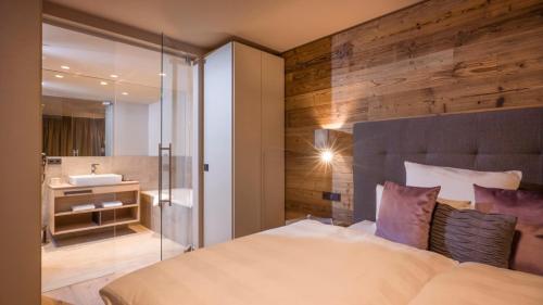 a bedroom with a bed and a bathroom with a sink at Posthotel Mayrhofen in Mayrhofen