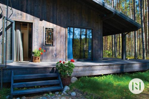 a wooden cabin with a porch with a bench and flowers at Rabarberi LV just 15min walk to SeaSide in Saulkrasti