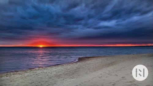una puesta de sol sobre el océano con una playa de arena en Rabarberi LV - SeaSide Village, en Saulkrasti