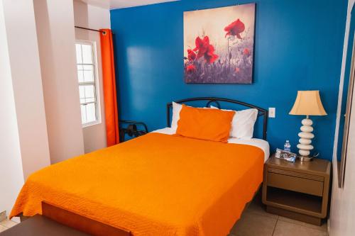 a blue bedroom with a bed with an orange bedspread at Hotel Revolución in Tijuana