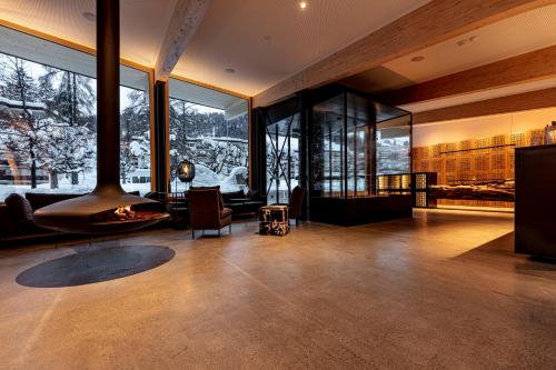 a living room with a fireplace and large windows at Hotel Arnica Scuol - Adults Only in Scuol