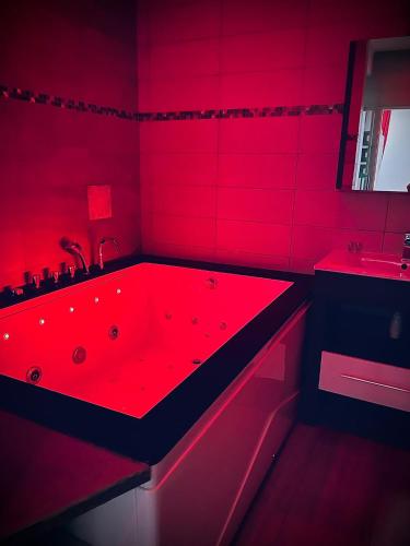 a red bathroom with a red bath tub with a sink at Suite Darcy & Spa in Dijon