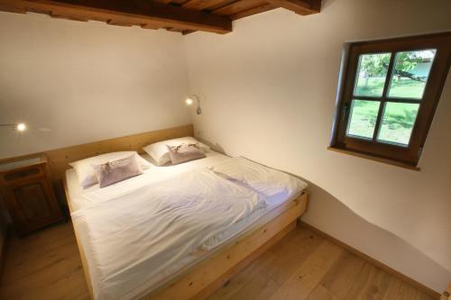 una camera da letto con un letto con lenzuola bianche e una finestra di Kellerstöckl Berg 77 a Sumetendorf