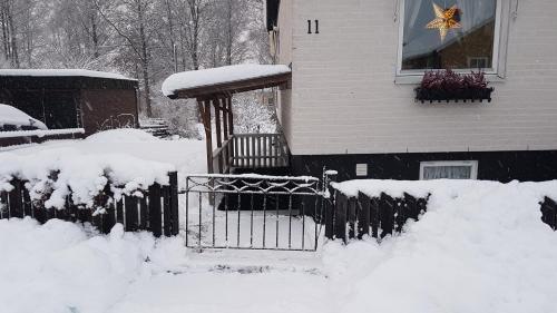 uma cerca coberta de neve em frente a uma casa em Hassellyckan em Ulricehamn