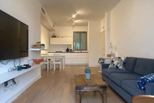 a living room with a blue couch and a kitchen at Laura Compound- Authentic 1 BR charming & specious in Tel Aviv