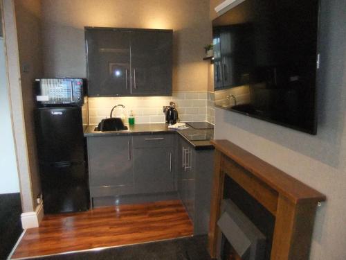 a kitchen with black cabinets and a black refrigerator at Dewsbury House in Blackpool
