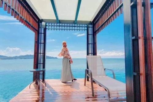 a woman standing on a porch next to the ocean at Serene Studio Imperium Residence Kuantan in Kuantan