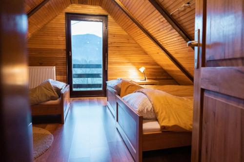 1 dormitorio en el ático con 2 camas y ventana en Vacation house Kula, en Jasenak