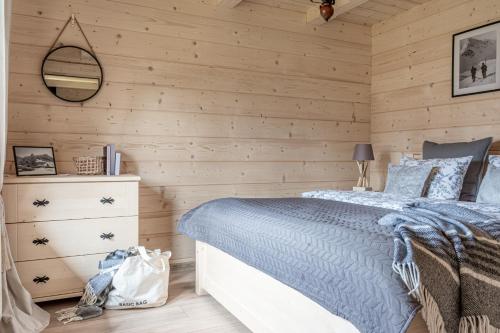 a bedroom with wooden walls with a bed and a dresser at Góralska Chata przy Dolinie Chochołowskiej - gorąca balia in Witów