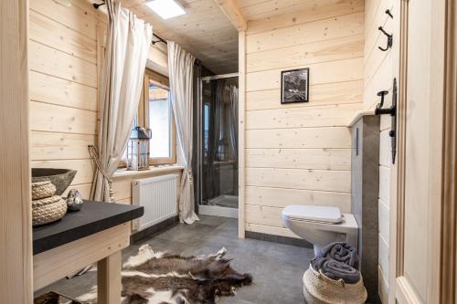 a wooden bathroom with a toilet and a sink at Góralska Chata przy Dolinie Chochołowskiej in Witów