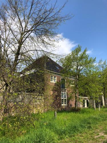 Monumental villa at the forest close to Haarlem and the beach في هيمستيده: منزل من الطوب القديم في حقل مع الأشجار