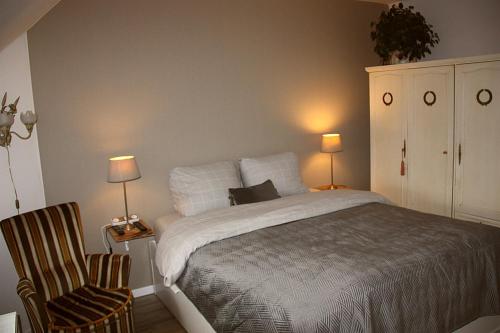 um quarto com uma cama, uma cadeira e 2 candeeiros em B&B De Veldwachter em Ravels