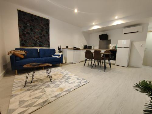 a living room with a blue couch and a kitchen at Bon encontre, Allée de la vierge in Bon-Encontre
