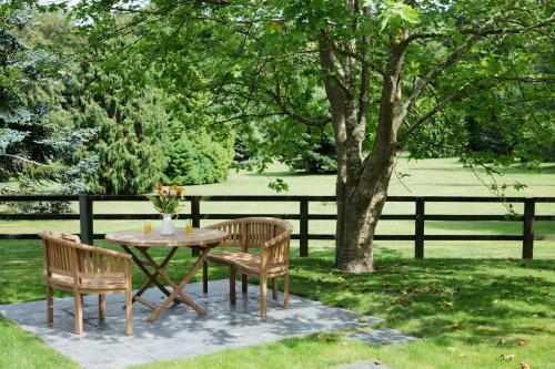 a table and two chairs and a table and a tree at Pinetum Garden Cottages in St Austell