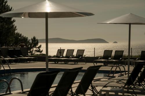 a pool with chairs and tables and an umbrella at Hotel Piramide in Portonovo