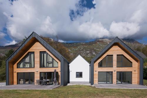 twee huizen met zwarte daken op een veld bij The Valley Queens in Bovec