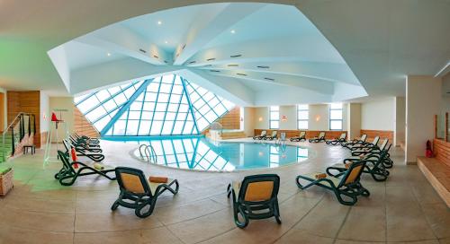 a large swimming pool in a building with chairs at Monte Baia Uludağ - Full Board Plus in Uludag