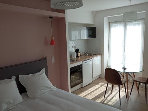 1 dormitorio con cama, mesa y cocina en Résidence Oceanica, en Bourbonne-les-Bains