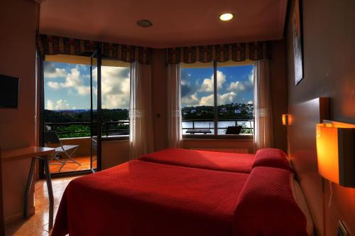 a bedroom with a red bed and a large window at Hotel Playa La Arena in Isla