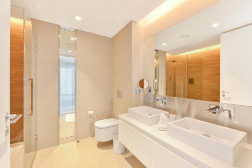 a bathroom with a sink and a toilet and a mirror at Island Paradise - Stylish 2BR on Bluewaters Island in Dubai