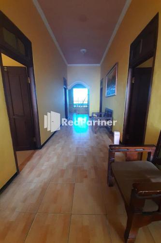 a living room with a wooden floor and a hallway at Bromo Indah Lestari Homestay Mitra RedDoorz in Pasuruan