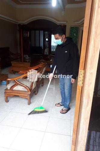 a man wearing a mask holding a mop at Bromo Indah Lestari Homestay Mitra RedDoorz in Pasuruan