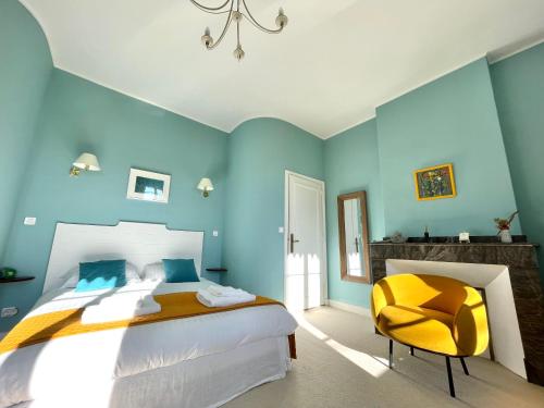 a blue bedroom with a bed and a yellow chair at La Mélanotte in Toulouse