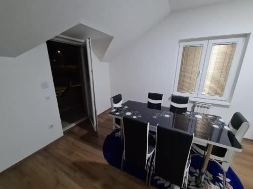 a dining room with a black table and chairs at Apartmani Mladenović in Kijevo