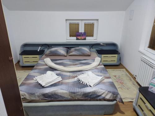 a bedroom with a bed with a blanket and two pillows at Apartmani Mladenović in Kijevo
