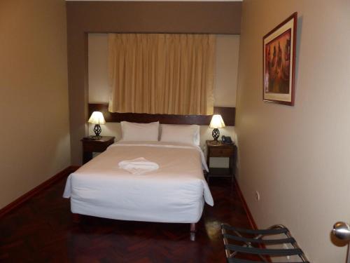 a bedroom with a bed and two lamps and a window at Suites Larco 656 Miraflores Lima in Lima