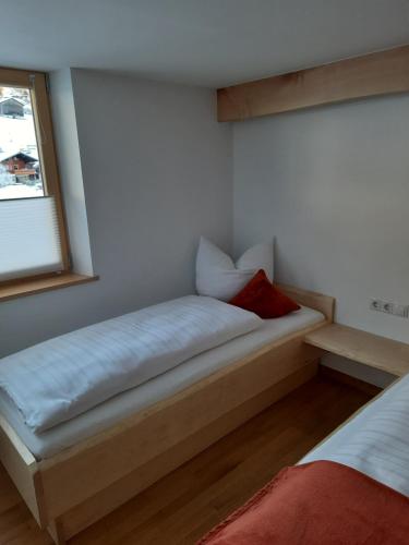 a small bed in a room with a window at Ferienwohnung Schrofamühli in Silbertal