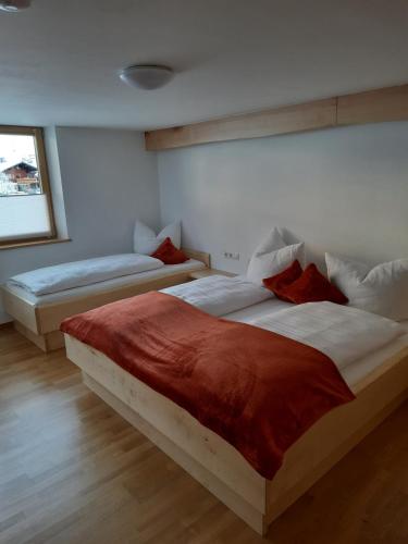a bedroom with two beds with red pillows at Ferienwohnung Schrofamühli in Silbertal
