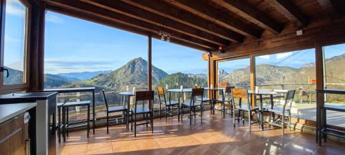 Una habitación con mesas y sillas en un balcón con montañas en Hotel Granja Paraíso, Oasis Rural & Bienestar en Cangas de Onís