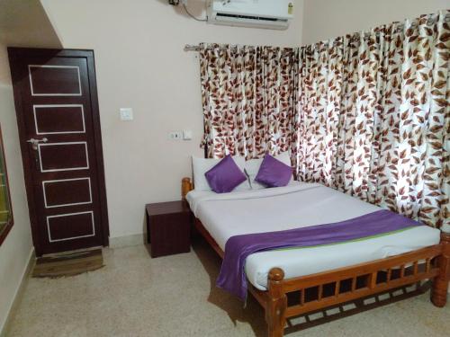 a bedroom with a bed with purple pillows at Reunion Villa in Udupi