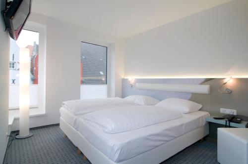 ein weißes Bett in einem Zimmer mit Fenster in der Unterkunft Hotel New Orleans in Wismar
