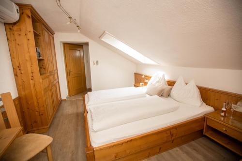 a bedroom with a bed with white sheets and pillows at Pension Knoll in Schörfling