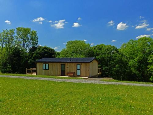 a small wooden cabin with a grass field at Shropshire Lodges - Romantic Luxury Hot Tub Breaks in Bridgnorth