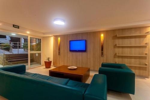 a living room with a blue couch and a tv at Pipa’s Bay flat 213 in Pipa