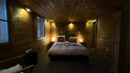 een slaapkamer met een groot bed in een houten kamer bij mini duplex dans chalet in Saint-François-Longchamp