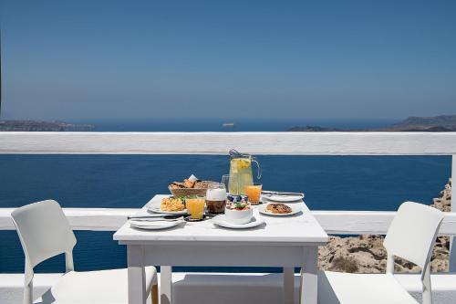 Apeiron Blue Santorini - Sustainable Adults Only 14 Plus في فيرا: طاولة مع طعام ومشروبات على شرفة