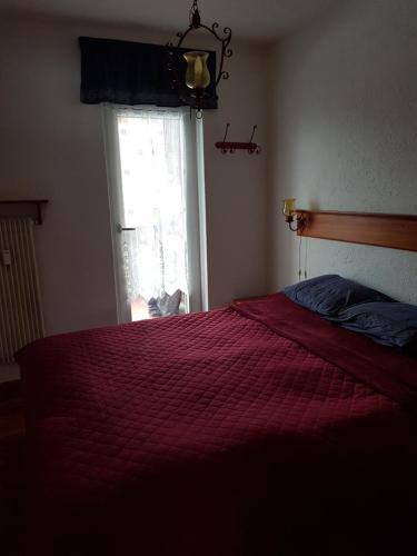 una camera da letto con un letto con un piumone rosso e una finestra di Trento- Monte Bondone Appartamento tipico di montagna a Norge