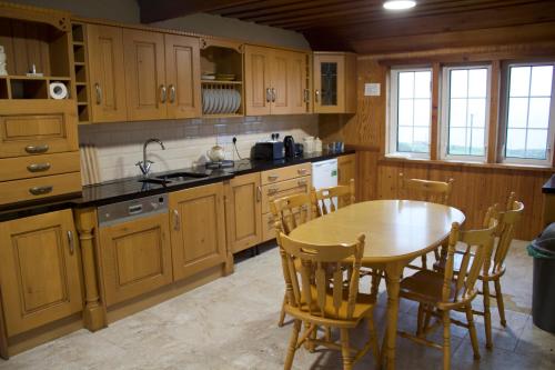 una cocina con armarios de madera, mesa y sillas en Dave's Big House, en Kilcar