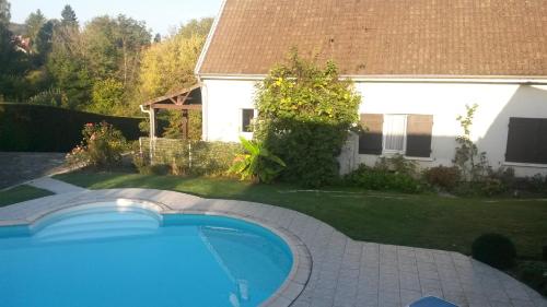 a swimming pool in a yard next to a house at la Maison d'Arbouet in Nanteuil-la-Fosse
