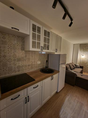 a kitchen with white cabinets and a sink and a couch at Apartments Vraneš Tivat in Tivat
