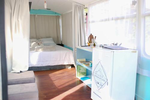 a bedroom with a bed and a desk with a refrigerator at Combi Bus Dreamcatcher in Sarchí