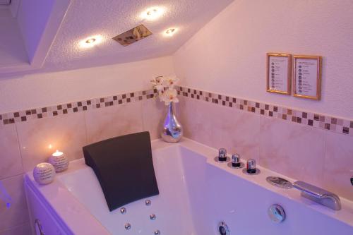 a white bath tub with a vase of flowers on it at Pension Knoll in Schörfling