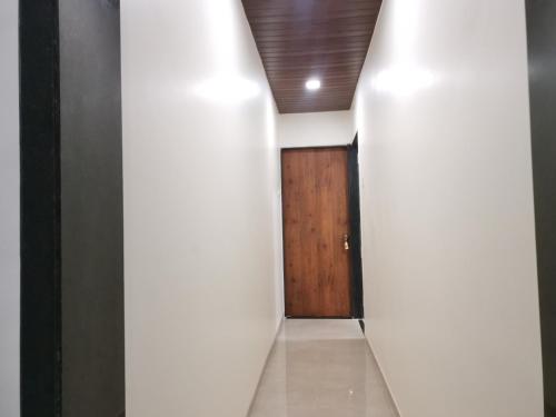 a hallway with white walls and a wooden door at Mahalaxmi Executive in Kolhapur