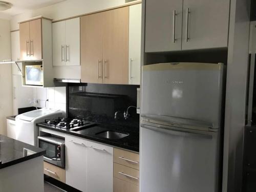 uma cozinha com armários brancos e um frigorífico de aço inoxidável em Lindo Apartamento 2 Quartos 5 min da Praia de BC em Balneário Camboriú