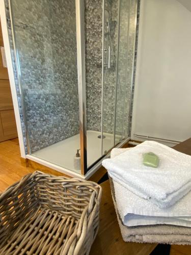 une douche avec une porte en verre à côté d'un panier dans l'établissement La VILLA en BAIE, au Crotoy