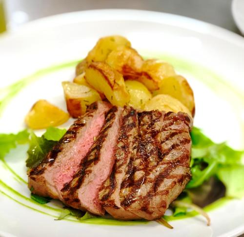 a plate of steak and vegetables on a plate at Hotel Diana in Valdobbiadene